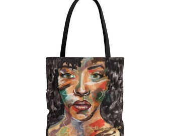 May include: A black tote bag featuring a colorful, painterly portrait of a person with dark curly hair and green eyes. The artwork uses expressive brushstrokes in shades of red, green, and brown, with a gold signature at the bottom right corner.