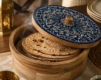 Puede incluir: Un recipiente redondo de madera que contiene una pila de pan plano, con vapor saliendo del contenido. La tapa presenta una superficie azul oscuro decorada con un intrincado patrón floral multicolor y un pequeño pomo de madera central.