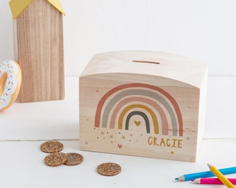 Puede incluir: Huchita de madera con forma de arcoíris con una ranura en la parte superior. La huchita está pintada con un arcoíris, estrellas y el nombre "Gracie".