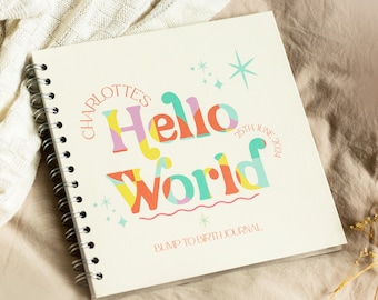 Könnte beinhalten: Ein cremefarbenes Spiralbuch mit dem Text "Charlotte's Hello World 25th June 2024" in bunten Buchstaben. Das Buch hat eine Wellenlinie und Sterne auf dem Einband. Der Text "Bump to Birth Journal" ist unten auf dem Einband gedruckt.