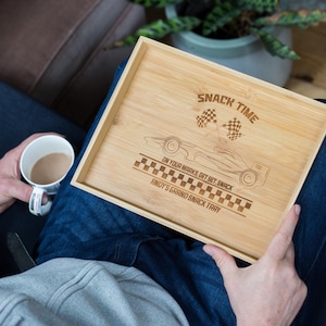 Può includere: Un vassoio per snack in legno con un design di auto da corsa e il testo "Snack Time On Your Marks Get Set Snack Andy's Grand Snack Tray".