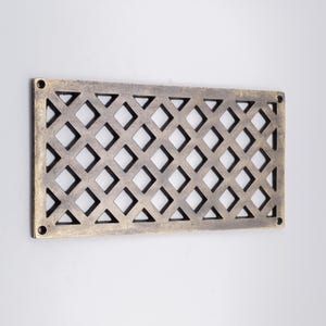 May include: A rectangular brass vent cover featuring a repeating diamond lattice pattern. The metal surface has an aged, darkened finish with visible screw holes located at each of the four corners for mounting purposes on a flat surface.