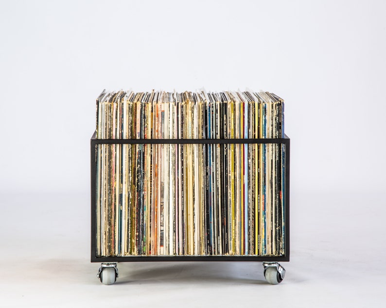 Front view of a minimalist black metal vinyl record storage cart filled with LPs, showing colorful record spines and mounted on four rubberized wheels for easy mobility.