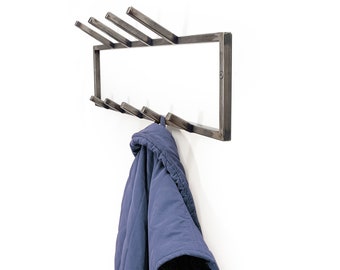 May include: A metal coat rack with six hooks, mounted on a white wall. A blue jacket is hanging on one of the hooks.