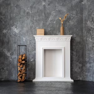 Minimalist black metal indoor firewood rack beside a white decorative fireplace on a dark textured wall, showcasing modern Scandinavian home decor.