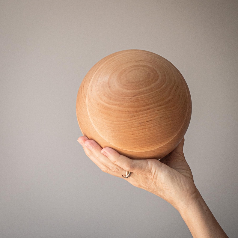 Hand holding a large wooden ball.