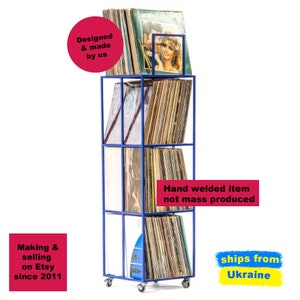 Angled view of blue four-tier metal vinyl record stand on wheels, fully loaded with LP albums, minimalist square steel frame, hand-welded in Ukraine.