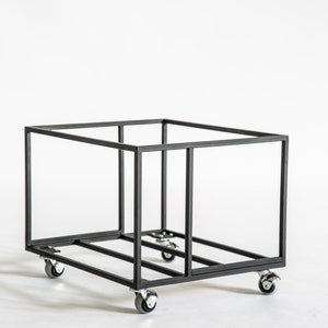 Angled view of an empty black metal vinyl record cart with a minimalist open-frame design, featuring four caster wheels for easy movement and industrial-style construction.
