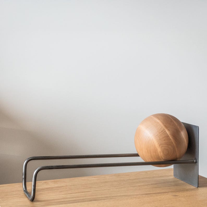 Minimalist desktop metal rack for vinyl LP records or books and holding wooden ball.
