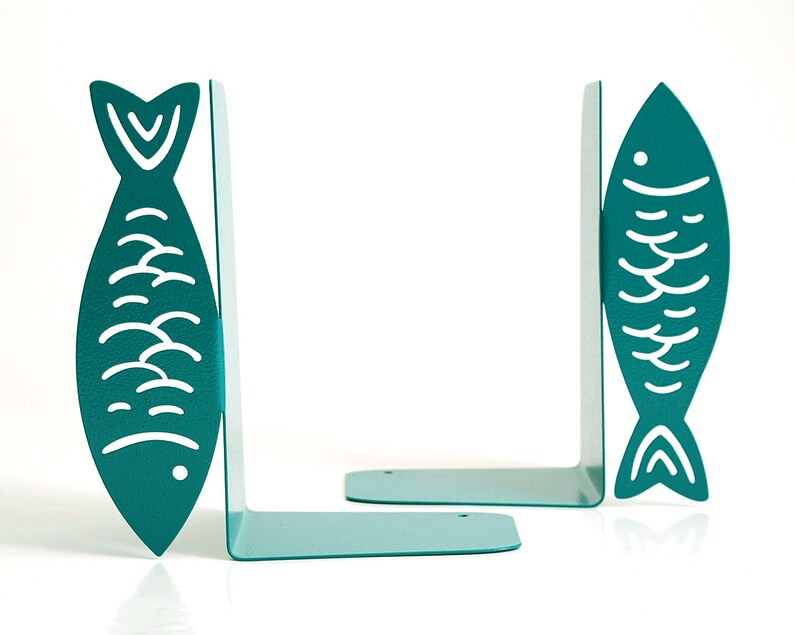 May include: A pair of teal blue metal bookends shaped like fish with white outlines. The fish have a simple design with scales and a fin.
