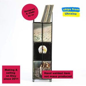Front view of tall four-tier metal vinyl record stand on wheels, loaded with LP albums, minimalist square steel frame, handmade and hand-welded in Ukraine.