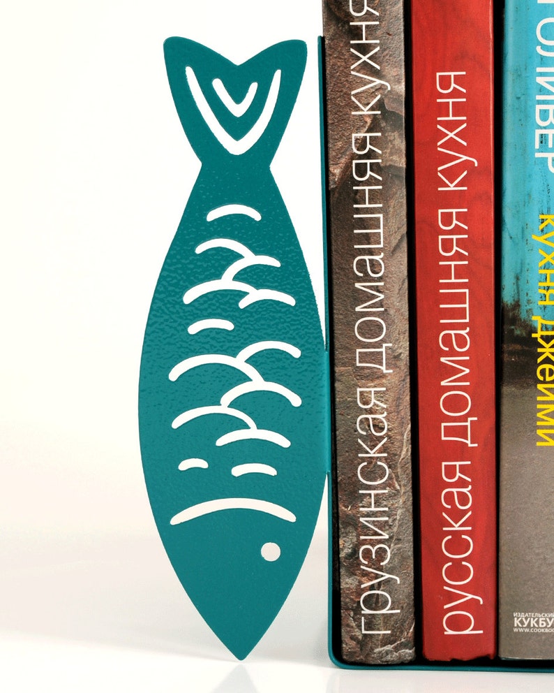 May include: Teal blue metal fish bookends holding up three books with titles in Russian and Georgian. The titles are "Грузинская домашняя кухня", "Русская домашняя кухня", and "ИМПЕрия КУХНИ".