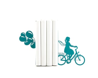 May include: Teal blue bookends featuring a silhouette of a girl riding a bicycle with balloons in the background.
