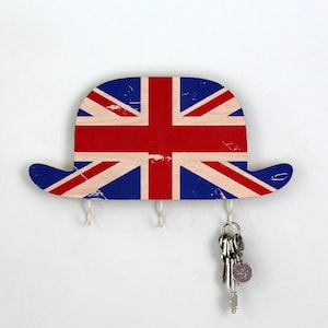 May include: A wooden key holder shaped like a bowler hat with the Union Jack flag printed on it. The hat has four hooks for hanging keys.
