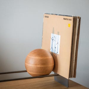 Minimalist rack with vinyl LP records and holding wooden ball.