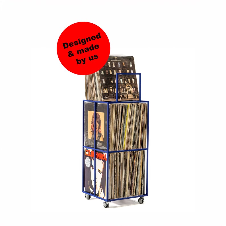 May include: A blue metal record storage unit with wheels, holding a collection of vinyl records. The unit has a sign that reads "Designed & made by us".