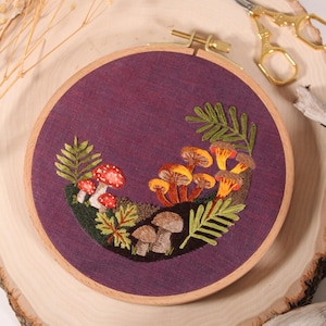 mushroom embroidery on purple fabric in an embroidery hoop