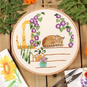 an embroidery of a sleeping cat on a front porch surrounded by purple morning glory flowers