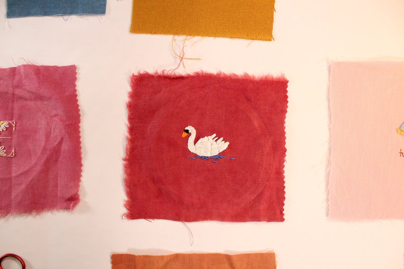 Red linen fabric patch with an embroidered swan on it.