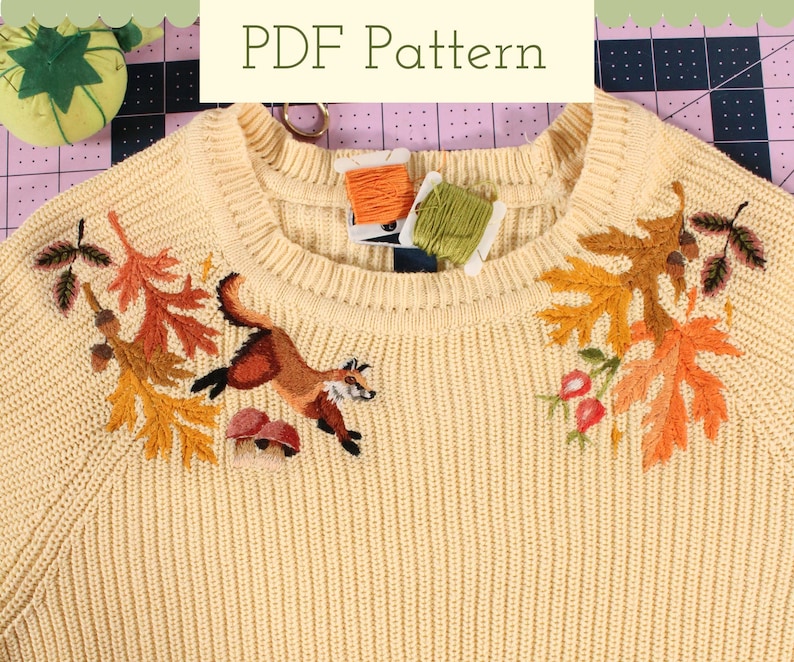 embroidery pattern for a woodland fox leaping over mushrooms surrounded by colorful leaves, acorns, and rose hips