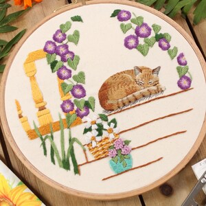 an embroidery of a sleeping cat on a front porch surrounded by purple morning glory flowers