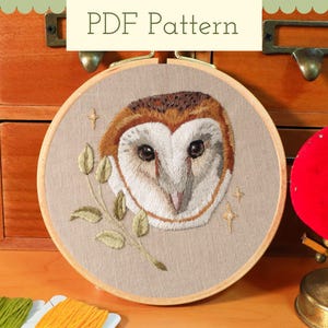 Peut inclure: Un cercle à broder rond avec un motif de hibou détaillé. Le hibou a des plumes marron et blanches, sur un fond beige. Le texte "PDF Pattern" est en haut. La broderie comprend une branche avec des feuilles et des étoiles.