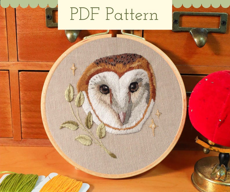 May include: A round embroidery hoop featuring a detailed owl design. The owl has brown and white feathers, with a beige background. The text "PDF Pattern" is at the top. The embroidery includes a branch with leaves and star accents.