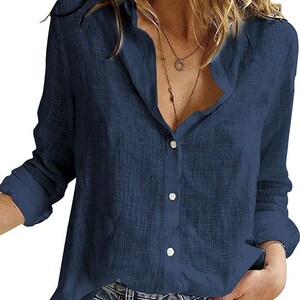 May include: A long-sleeved navy blue button-down shirt with a textured fabric finish, a classic collar, and a front button placket. The shirt features a relaxed fit with cuffed sleeves and is paired with blue denim jeans.