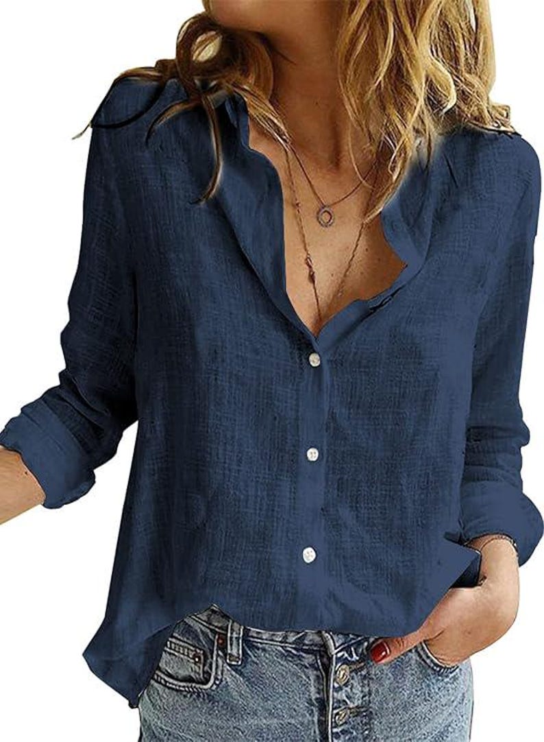May include: A long-sleeved navy blue button-down shirt with a textured fabric finish, a classic collar, and a front button placket. The shirt features a relaxed fit with cuffed sleeves and is paired with blue denim jeans.
