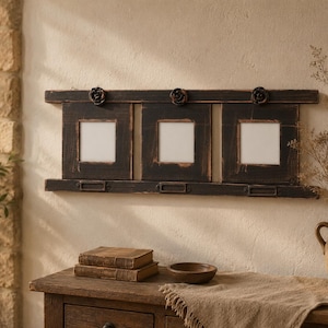 Könnte beinhalten: Ein horizontaler Wandbilderrahmen aus Holz mit drei quadratischen Öffnungen für Fotos. Der Rahmen hat eine abgenutzte schwarze Oberfläche mit sichtbarer Holzmaserung, akzentuiert durch drei kleine, dunkle, blumenförmige Metallknöpfe.