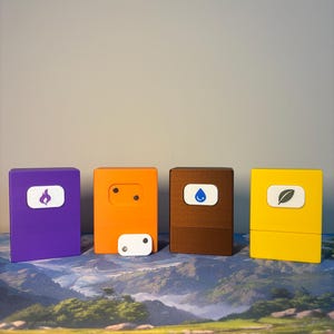 May include: Four rectangular storage boxes in purple, orange, brown, and yellow. The purple box features a white icon of a flame, the brown box a blue water drop, and the yellow box a leaf. The orange box has a small white rectangular piece with two dots.