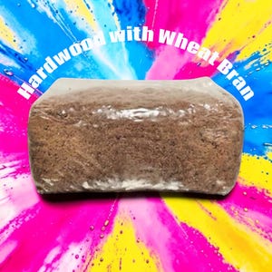May include: A rectangular block of brown, granular substrate material encased in a clear plastic bag. The text "Hardwood with Wheat Bran" is printed in white letters across the top of the image against a vibrant, multi-colored background.