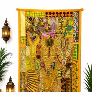 Puede incluir: Un tapiz rectangular con un diseño de patchwork vibrante en tonos amarillos, dorados y verdes. El tejido se compone de varios paneles de tela con bordados intrincados, motivos florales, lentejuelas y pequeños espejos.