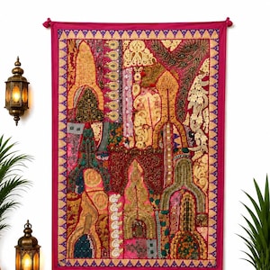 Op de afbeelding: Een rechthoekig wandkleed met een levendig patchwork van geborduurde stoffen in tinten magenta, goud en dieprood. Het textiel toont ingewikkeld metaaldraadwerk, kraalversieringen en boogvormige architecturale motieven.