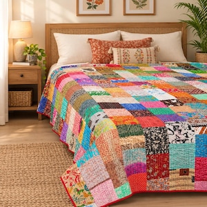May include: A rectangular patchwork quilt featuring a vibrant array of multicoloured fabric squares with diverse floral, geometric, and abstract patterns. The quilt is stitched with visible running thread lines and finished with a solid red border.