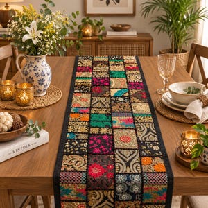 Puede incluir: Un camino de mesa rectangular con un diseño de parches de varios cuadrados de tela en colores vibrantes como rosa, verde, naranja y dorado. El camino está decorado con intrincados bordados, hilos metálicos y detalles de cuentas.