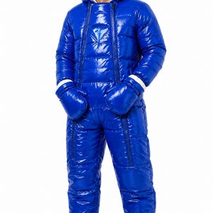 Puede incluir: Un mono acolchado de una pieza en color azul brillante con acabado de alto brillo, que incluye capucha con forro color crema, mangas largas, manoplas azules a juego con puños blancos y patucos integrados. Cierre de cremallera frontal.