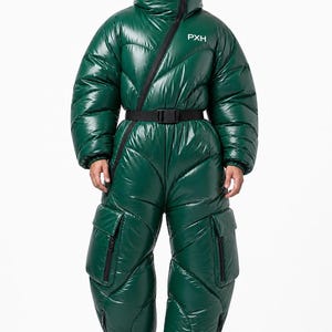 Op de afbeelding: Een glanzende donkergroene gewatteerde jumpsuit met een hoge kraag, een diagonale ritssluiting en een zwarte riem met gesp. Het kledingstuk heeft grote cargozakken op de dijen en de witte tekst PXH gedrukt op het bovenste borstgedeelte.