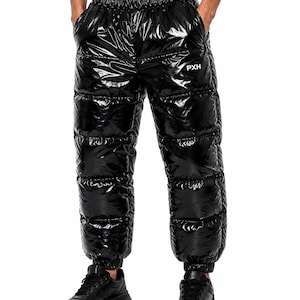Op de afbeelding: Zwarte gewatteerde pufferbroek met een hoogglans afwerking. Deze broek heeft een dikke elastische tailleband, elastische boorden bij de enkels en de witte tekst PXH gedrukt op de linkerdij. Het ontwerp is voorzien van horizontale stiksels.