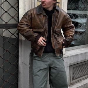 Jaqueta streetwear de pele de carneiro A2 com punhos canelados desgastados, estilo militar, feita à mão, com fecho de aba e botões de pressão, bolsos. Ideal para presentear.