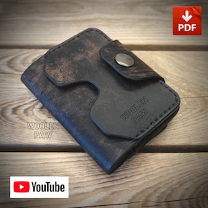 Può includere: Un portafoglio in pelle invecchiata marrone scuro con chiusura a patta fissata da un singolo bottone a pressione metallico. La parte anteriore del portafoglio presenta la scritta in rilievo WOOLEN PAW e cuciture visibili lungo i bordi.