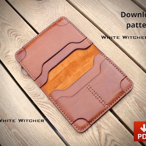 Könnte beinhalten: Ein beigefarbener Kartenhalter aus Leder mit mehreren Fächern, abgerundeten Ecken und dekorativen Kreuzstichen auf der Vorderseite. Der Text "Download pattern" und "WHITE WITCHER" ist sichtbar, sowie ein rotes quadratisches Symbol mit weißem Pfeil und "PDF".