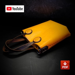 Könnte beinhalten: Eine leuchtend gelbe Ledertasche mit dunkelbraunen Ledergriffen, die mit runden gelben Lederaufnähern befestigt sind. Die Tasche hat sichtbare Nähte an den Kanten sowie ein YouTube-Logo oben links und ein PDF-Symbol unten rechts.