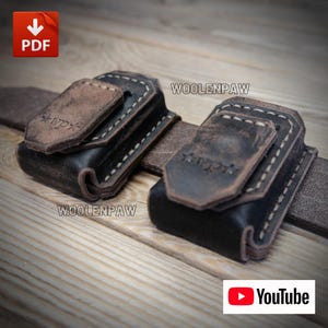 May include: A dark brown leather belt featuring two attached rectangular pouches with flap closures. Each pouch is stitched with light-coloured thread and embossed with the text WOOLENPAW and a star logo. The leather has a distressed finish.