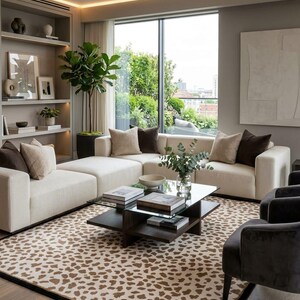 May include: A living room featuring a cream-coloured sectional sofa with brown and beige throw pillows, a glass-topped coffee table with a dark wood base, and a large area rug with a brown and cream animal print pattern on a light wood floor.