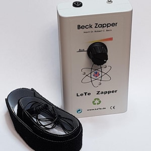 Könnte beinhalten: Ein weißes, rechteckiges elektronisches Gerät mit der Aufschrift Beck Zapper Nach Dr. Robert C. Beck und LeTe Zapper, ausgestattet mit einem schwarzen Drehknopf, einer Atomgrafik und einer Webadresse. Ein schwarzes Stoffband mit Kabel liegt daneben.