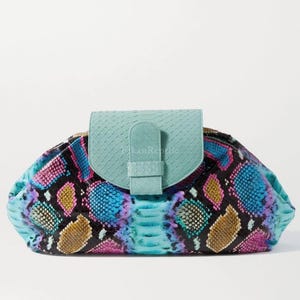 May include: A clutch bag featuring a snakeskin pattern in vibrant shades of blue, pink, purple, and gold. The bag has a solid light blue flap closure with a vertical strap detail. The text TikanReptile is printed on the center of the flap.