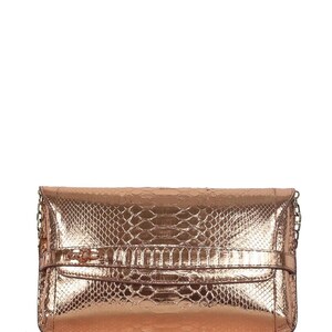 Pode incluir: Uma bolsa clutch metálica em tom de ouro rosa com um padrão texturizado de pele de cobra. A bolsa retangular possui uma tira horizontal sobre a aba frontal com um pequeno detalhe de nó decorativo e correntes metálicas finas nas laterais.