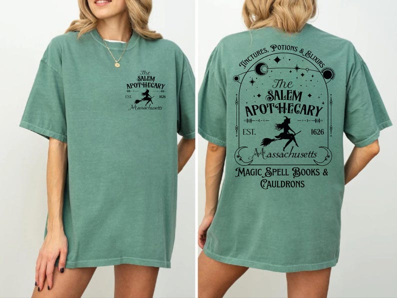 a woman wearing a green t-shirt with a design that includes text and graphics related to a witch-themed business called "The Salem Apothecary".