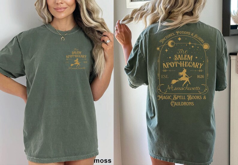A woman wearing a green t-shirt with text and graphics related to the Salem Apothecary.